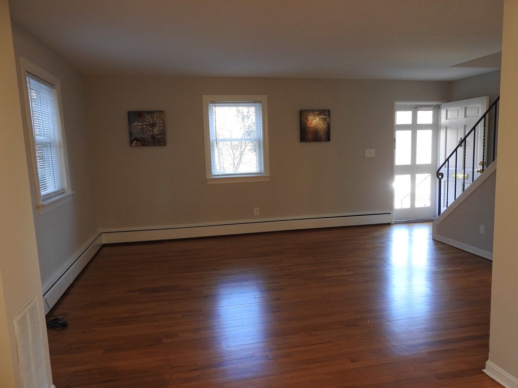 an empty living room with wooden floors and a staircase