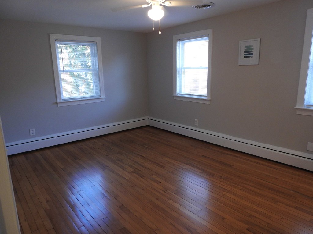 an empty living room with wooden floors and two windows