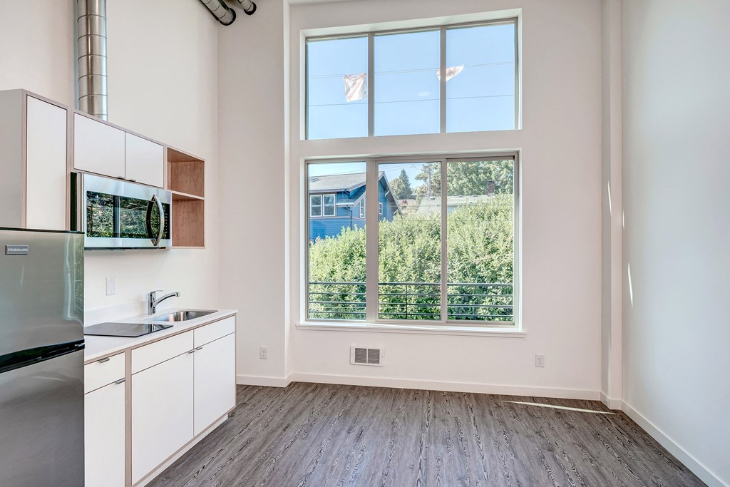 an empty apartment with a large window and a kitchen