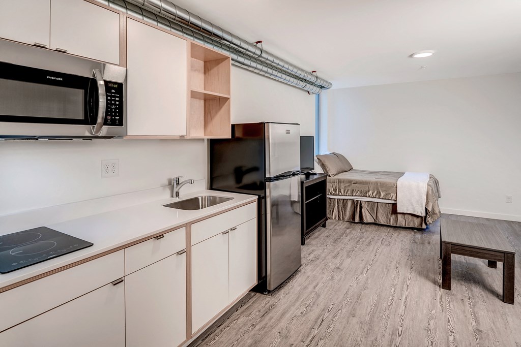 a kitchen with a sink and a refrigerator and a bed