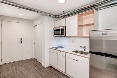 an empty kitchen with white cabinets and a stainless steel refrigerator