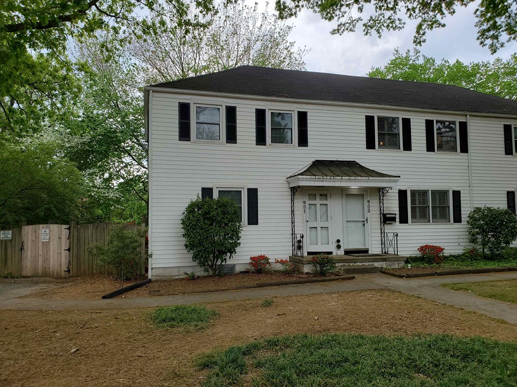 a white house with black shutters and a gravel driveway