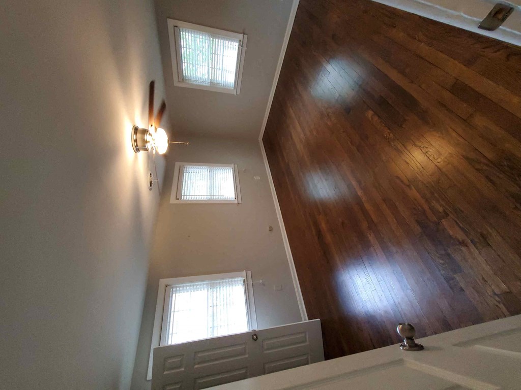 a view of a bedroom with a wooden floor and white walls
