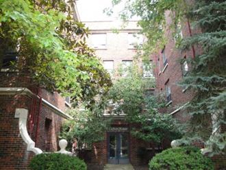 a brick building with trees and bushes in front of it