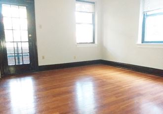 an empty living room with wood floors and two windows