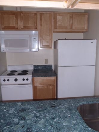 an empty kitchen with a stove refrigerator and microwave