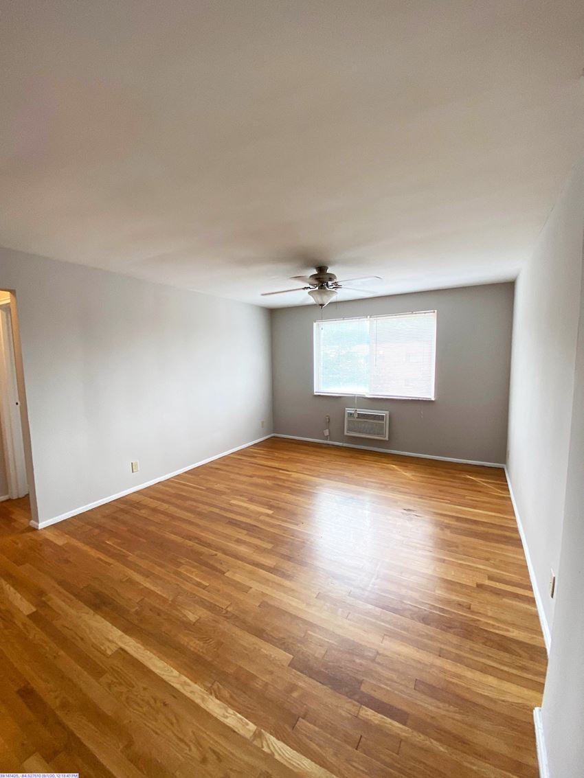 an empty living room with wooden floors and a ceiling fan