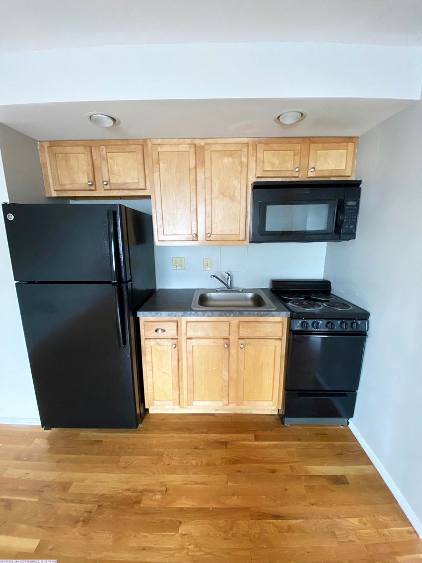 an empty kitchen with black appliances and wooden cabinets