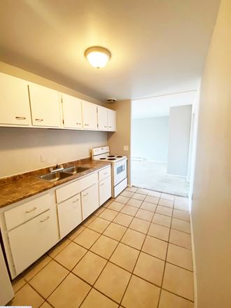 an empty kitchen with white cabinets and tiled flooring