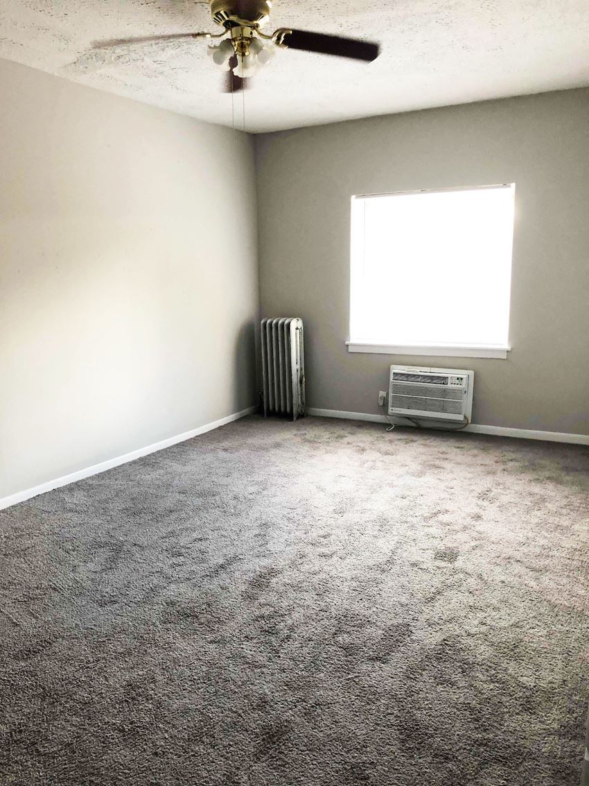 an empty room with carpet and a ceiling fan