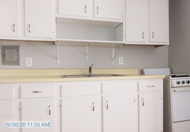 an empty kitchen with white cabinets and a sink