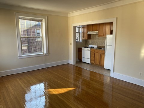 an empty living room and kitchen with wood floors