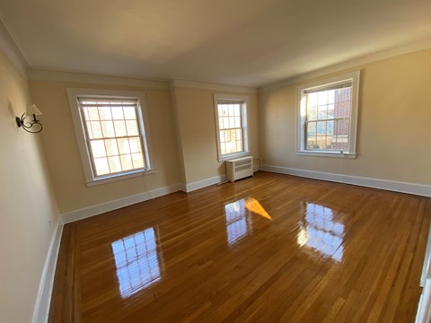 an empty living room with wooden floors and two windows