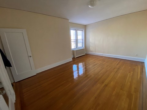 an empty living room with wooden floors and a window