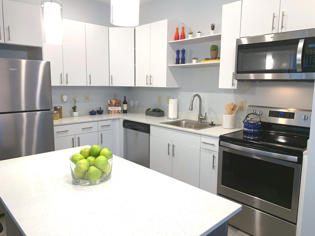 a white kitchen with stainless steel appliances and a bowl of apples