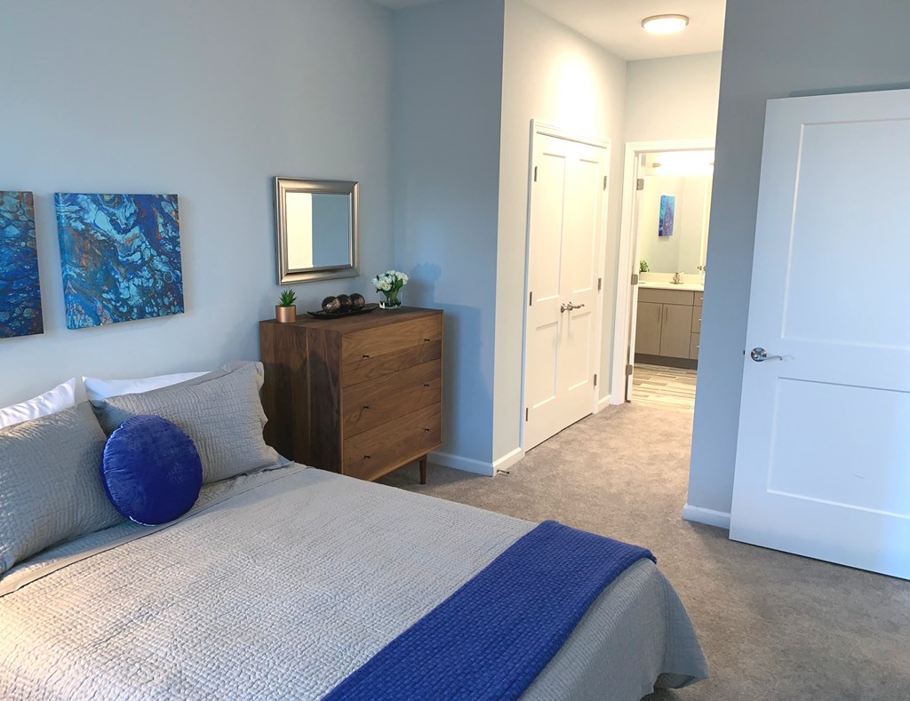 a bedroom with a bed and a dresser and a door to a bathroom