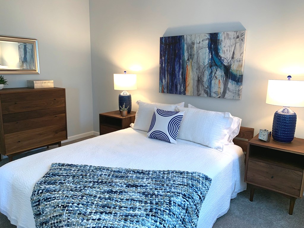 a bedroom with a bed and two nightstands and a painting on the wall