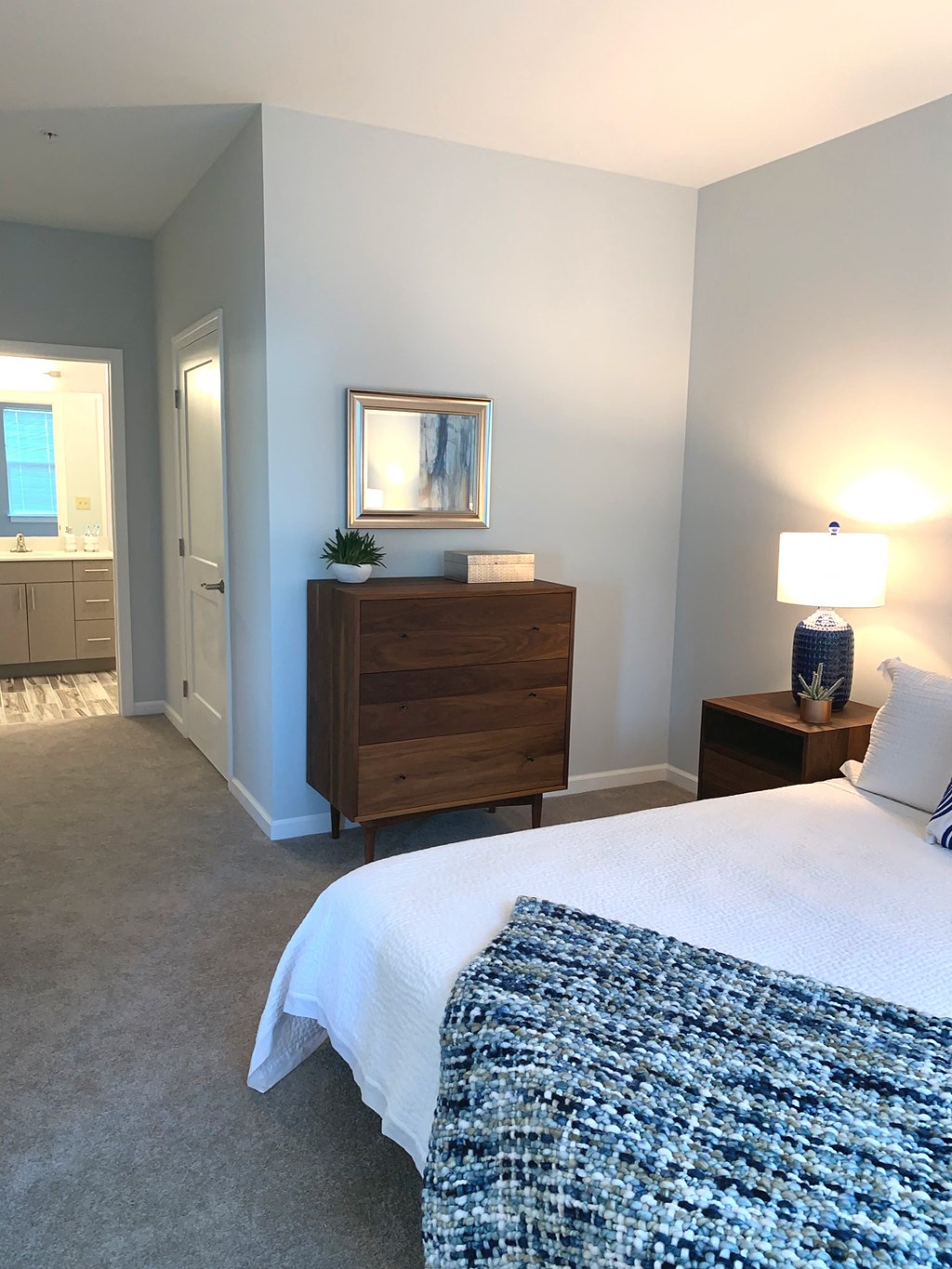 a bedroom with a bed and a dresser and a bathroom