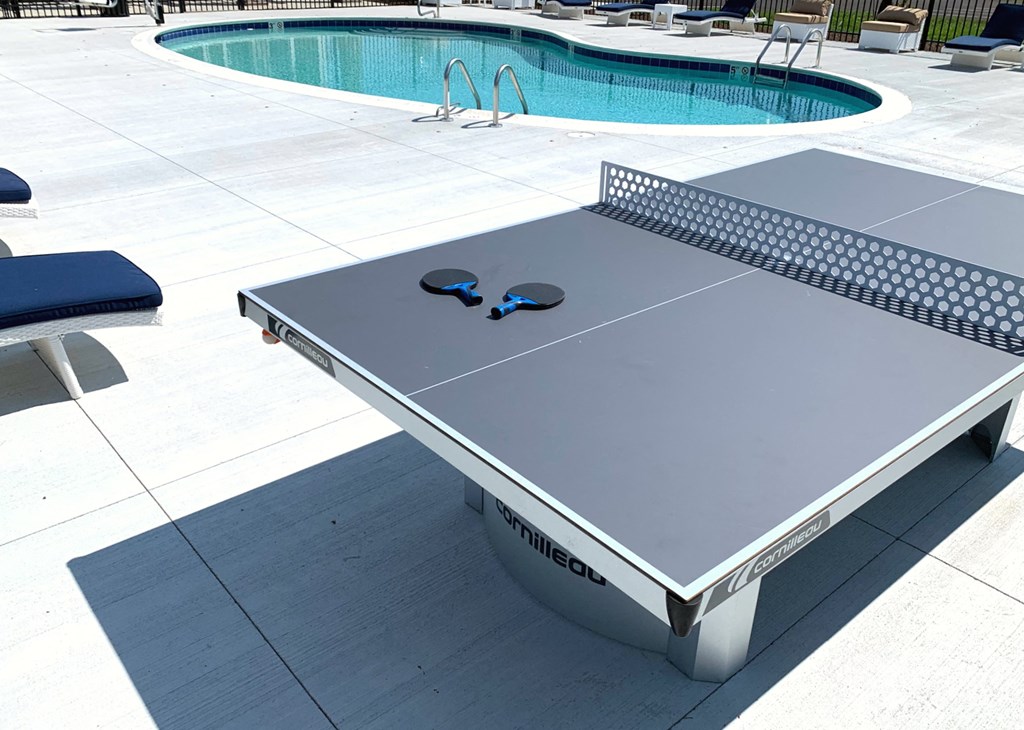 a ping pong table next to a swimming pool