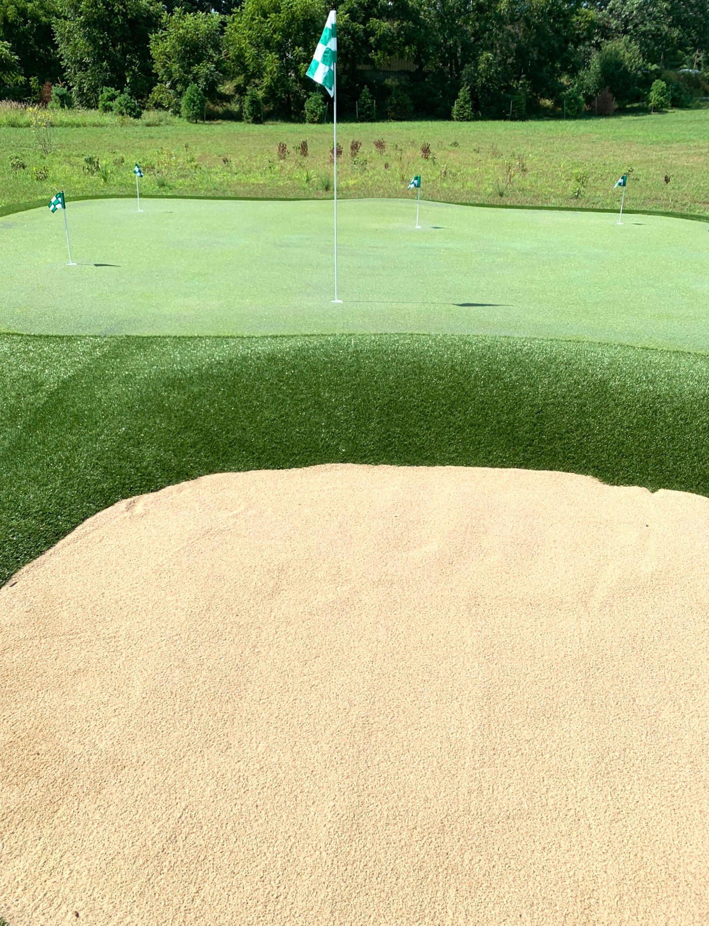 a golf course with a flag on top of a sand bunker