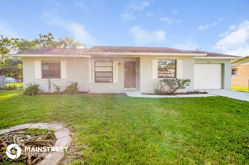 a small white house with a yard and grass