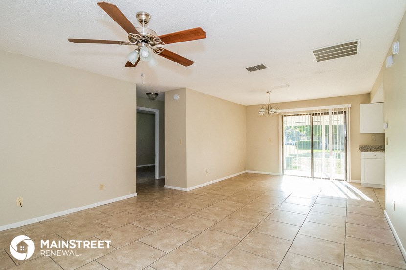 an empty living room with a ceiling fan and tiled floor