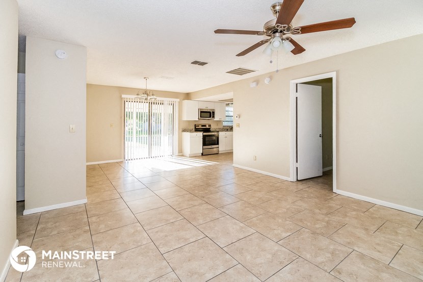 a living room with a ceiling fan and a door to a kitchen