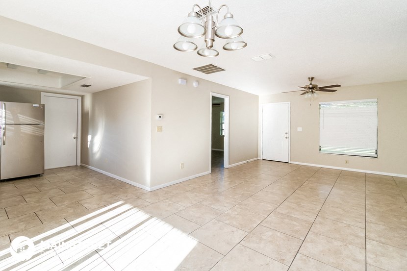 an empty kitchen and living room with a stainless steel refrigerator