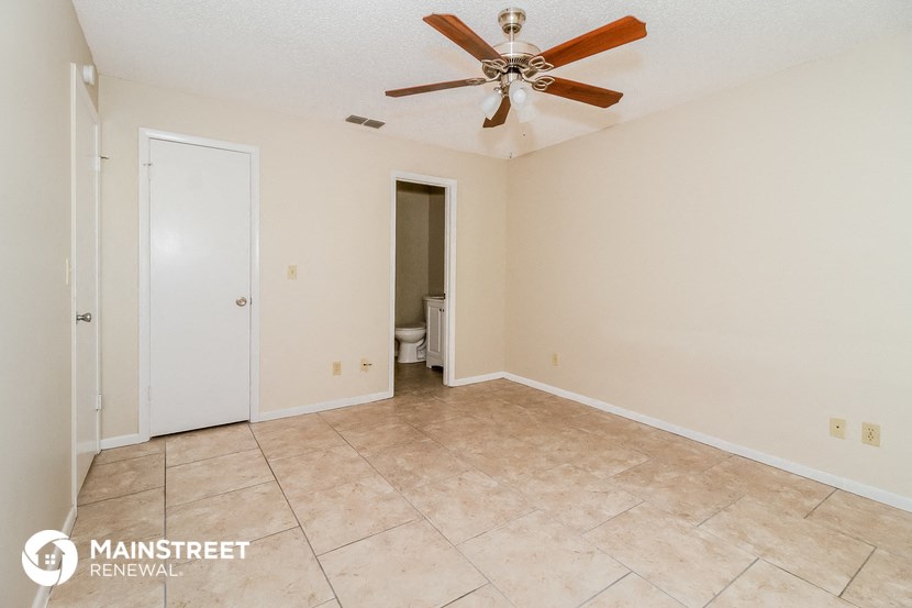 the spacious living room with tile flooring and a ceiling fan