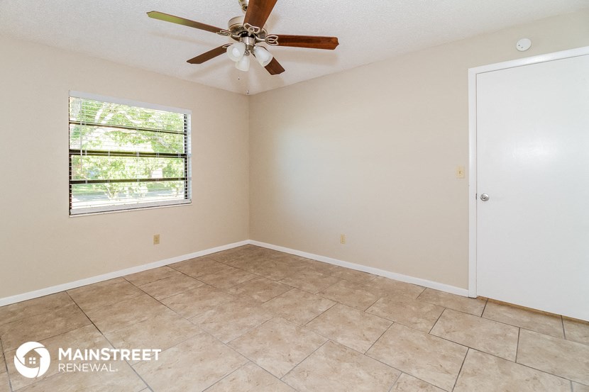 the living room of a home with a large window and a ceiling fan