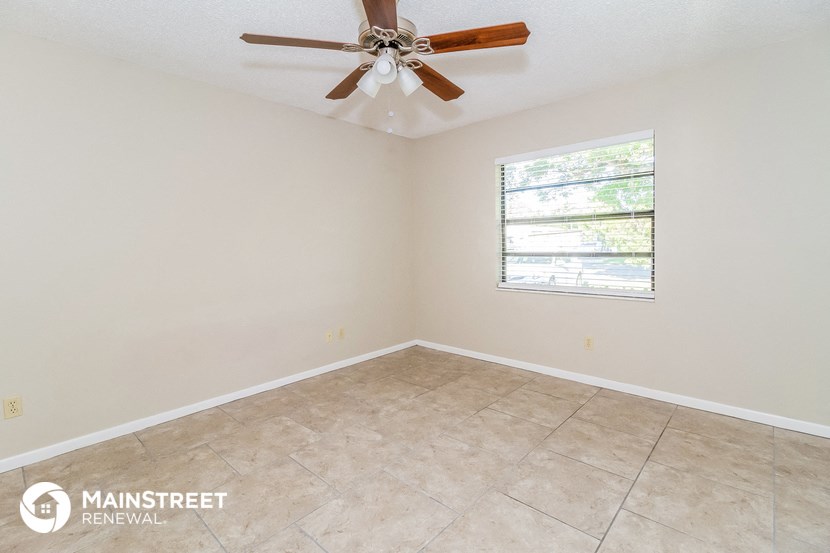 the living room of this home has a large window and a ceiling fan