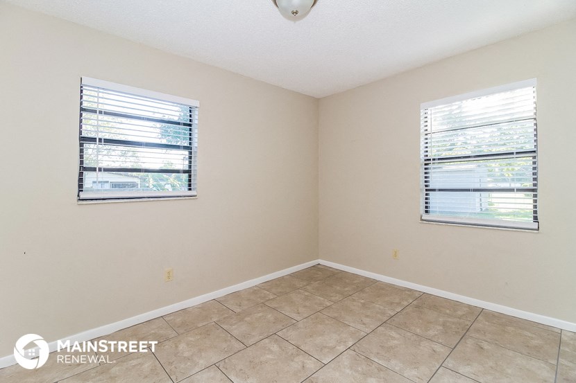 the living room of a home with a tiled floor and two windows