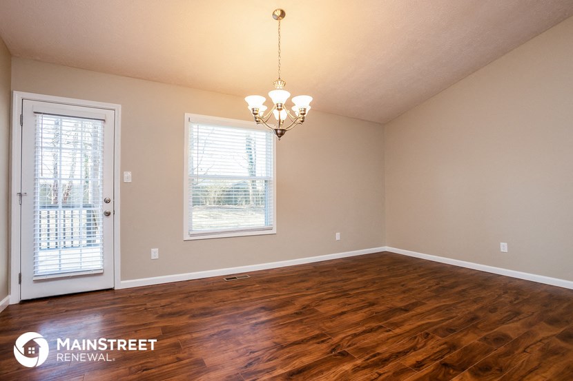 the living room of a home with wood flooring and a door