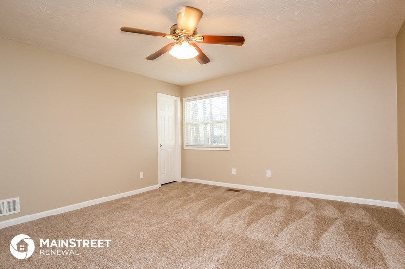 the spacious living room with carpeting and a ceiling fan