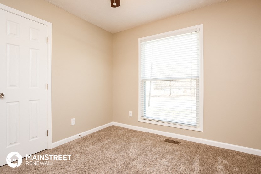 a carpeted room with a window and a white door