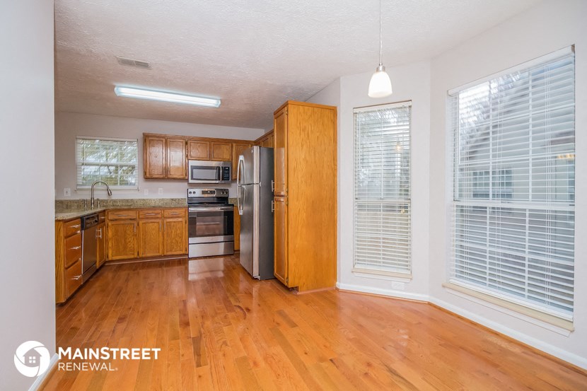 an empty kitchen with wood flooring and stainless steel appliances