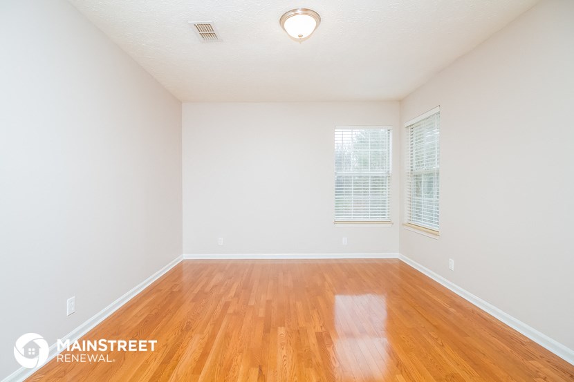 the spacious living room with wood floors and white walls