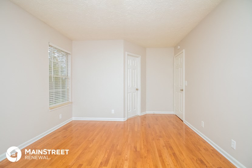 a spacious living room with wood floors and white walls