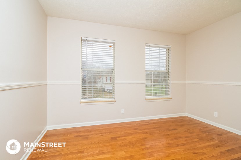a bedroom with wood floors and white walls and windows