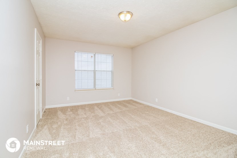 the spacious living room with carpeting and a window