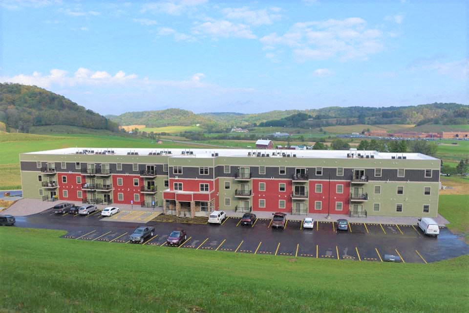 an aerial view of an apartment building with cars in a parking lot