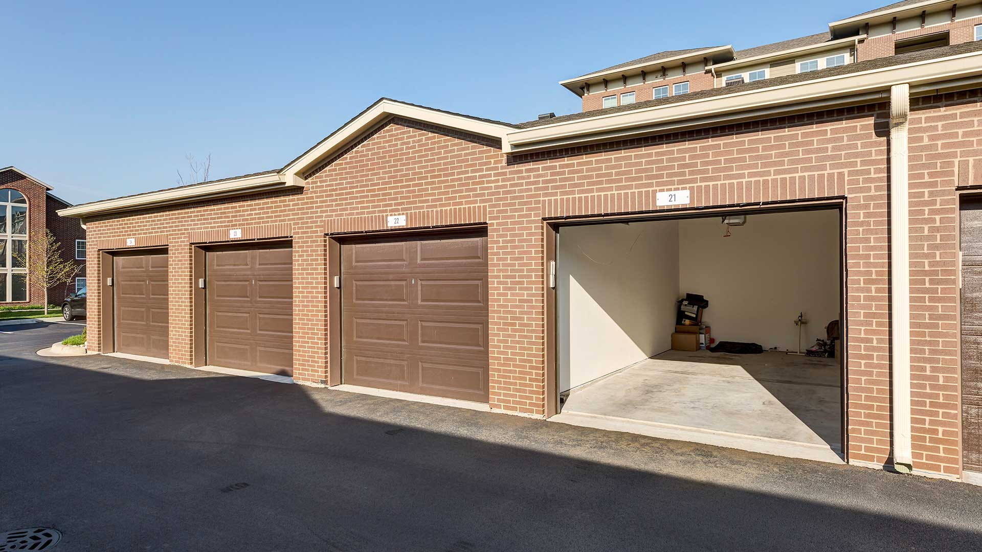 A row of detached garages. The closest is open, with a few belongings stored in the back.