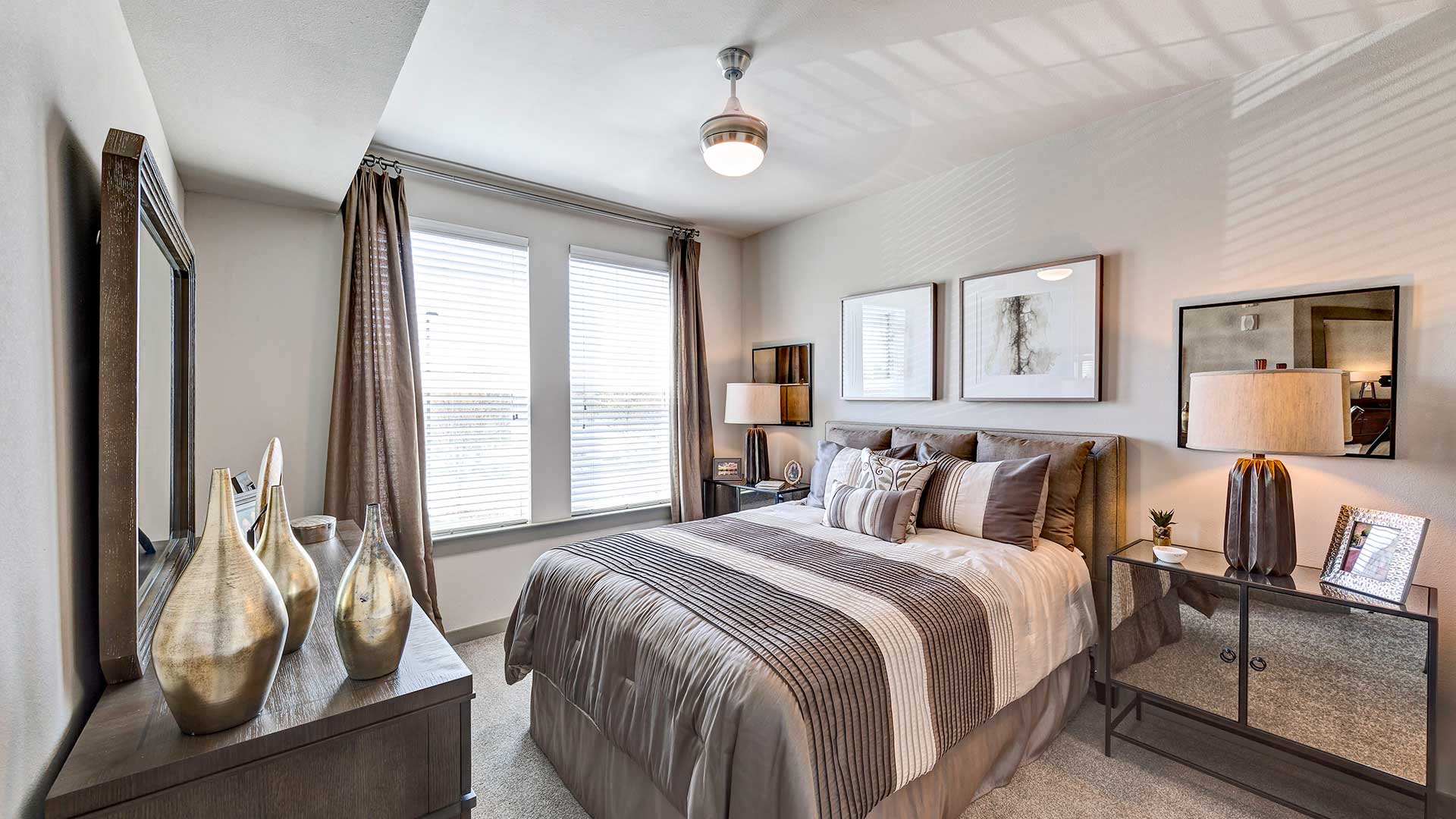 A large bed is set against the wall with an end table and lamp on each side. The window shows a bright day outside.