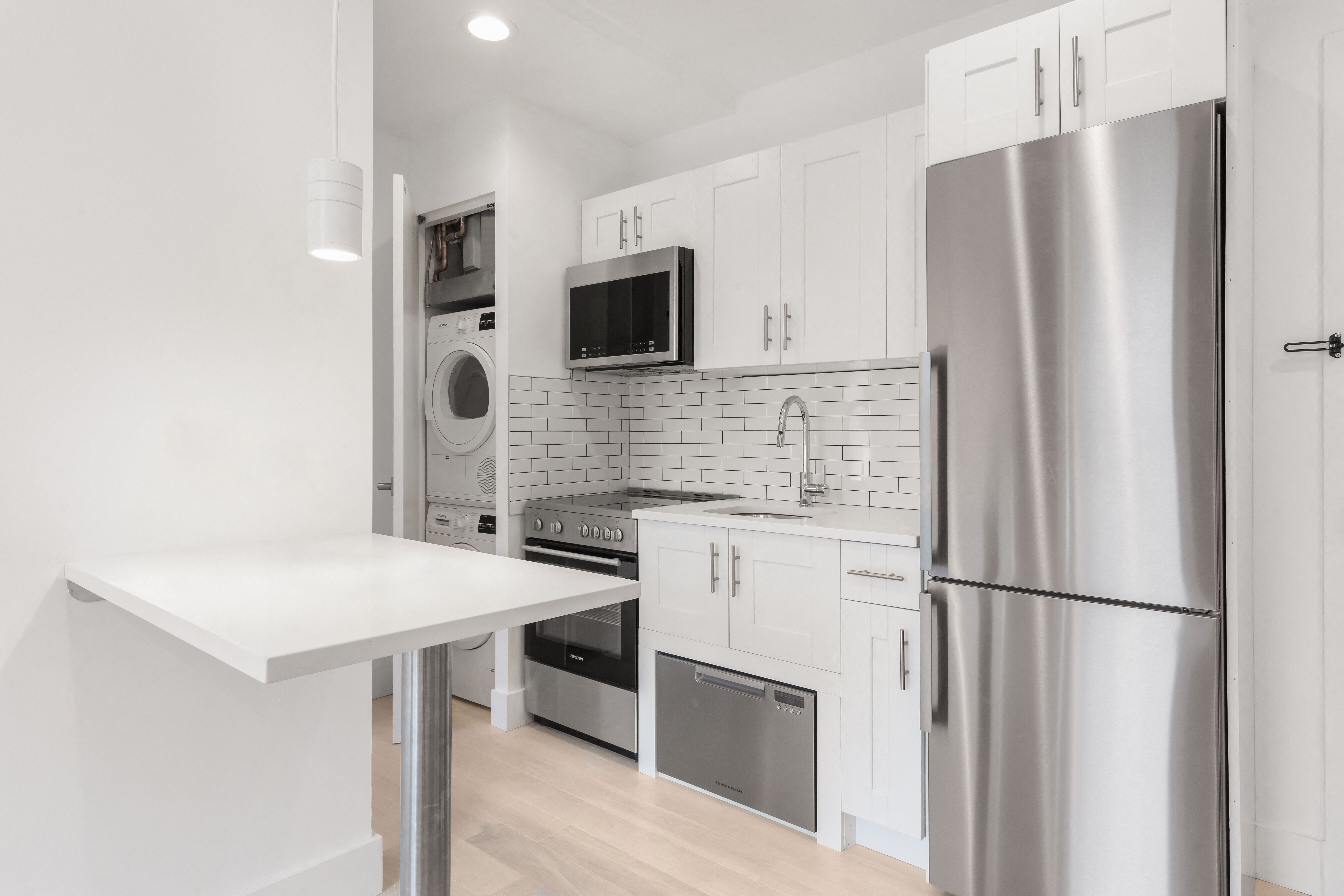 A modern kitchen with a stainless steel refrigerator and white cabinets.