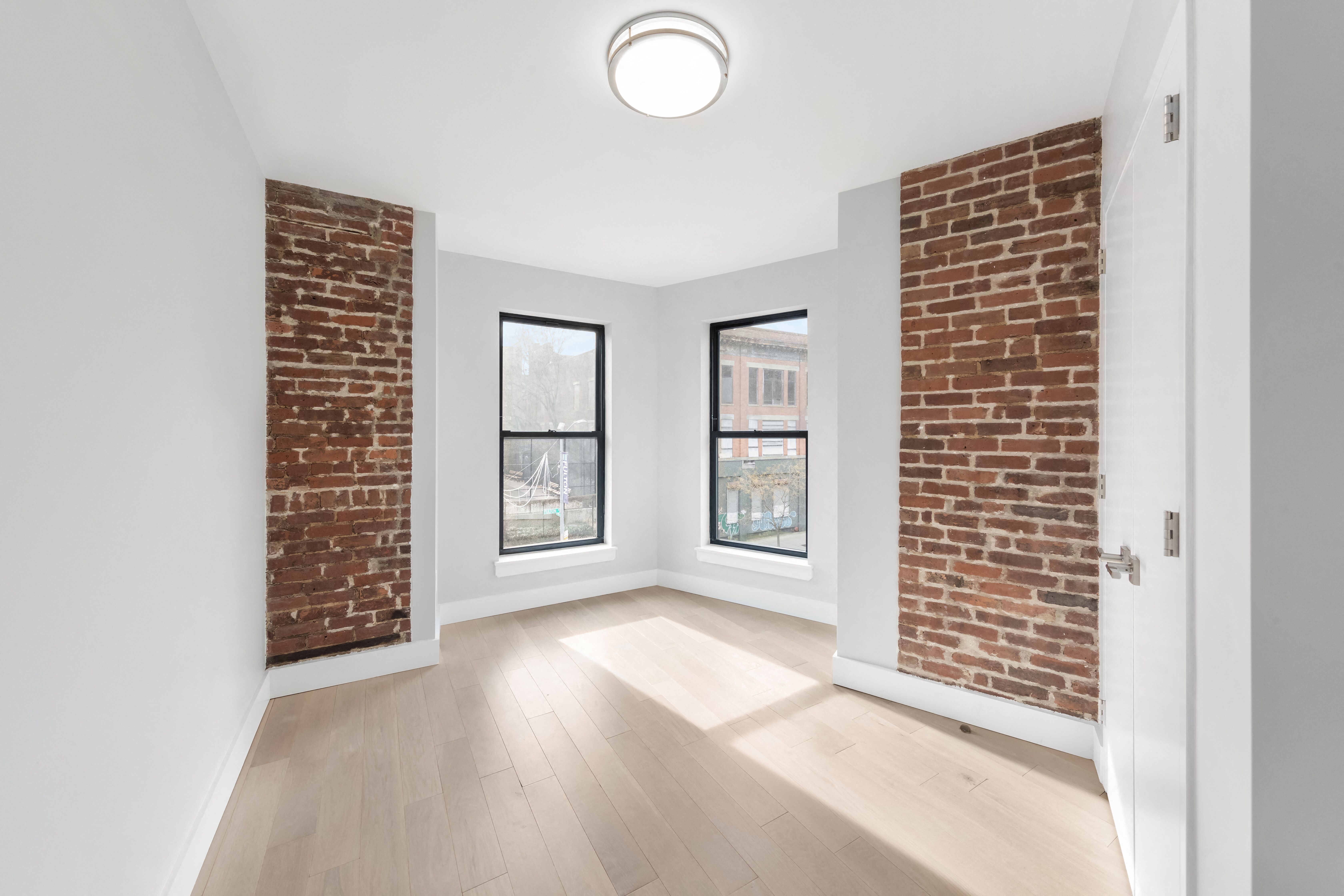 A room with a brick wall and a window overlooking a cityscape.