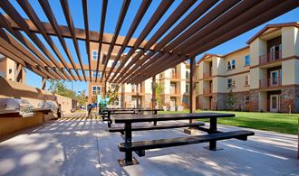 a communal picnic area with benches and awnings at an apartment complex