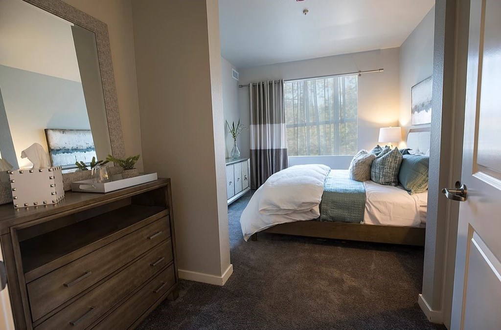 a bedroom with a bed and a dresser and a window