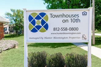 a sign for townhouses on 10th in front of a lawn