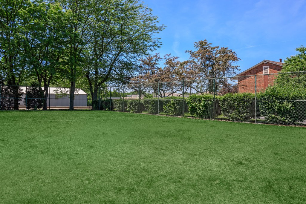 a yard with a fence and trees and a building in the background
