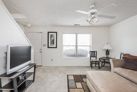 a living room with a ceiling fan and a television